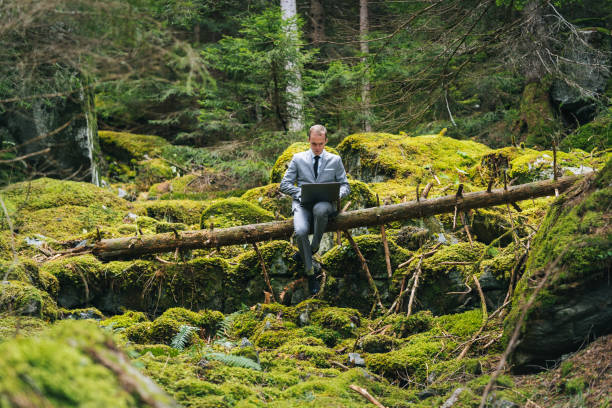 He relaxes on fallen tree and hosts meeting on laptop